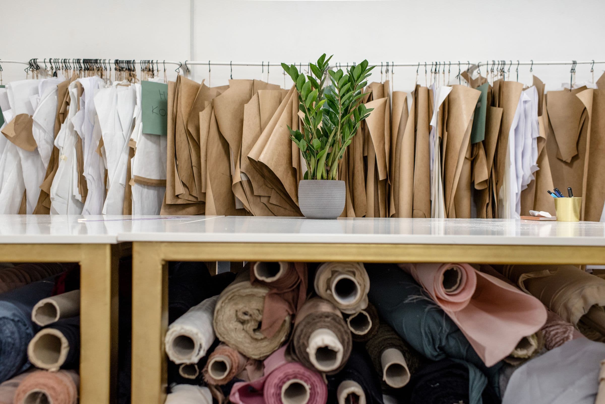 Rolls of fabric and paper pattern pieces stacked in the atelier